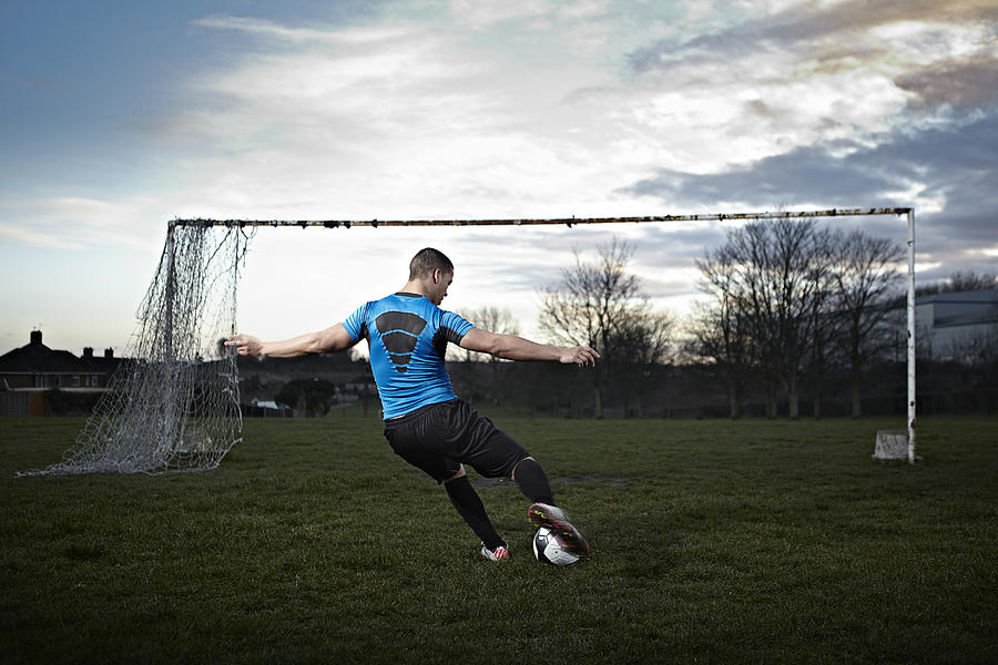 Mixed race male taking a penalty kick Photograph by Jamie Garbutt