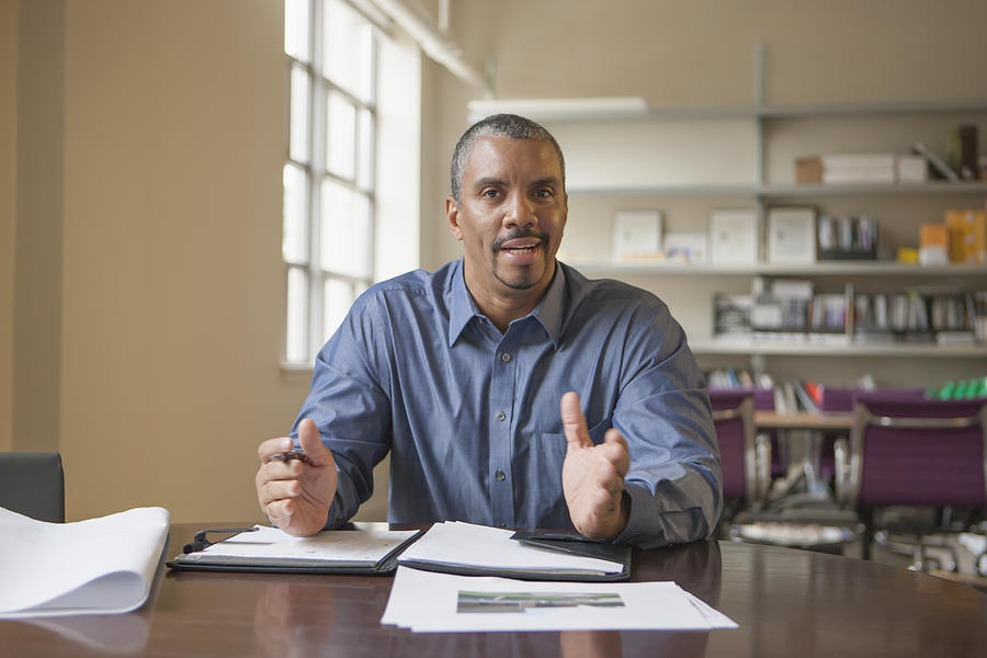 Mixed race man talking at desk Photograph by John Fedele