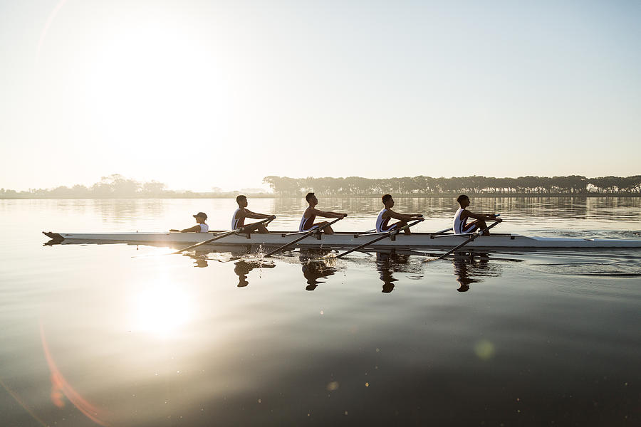 Mixed race rowing team training on a lake at dawn Photograph by Alistair Berg