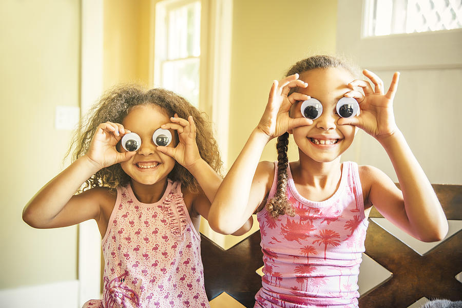 Mixed race sisters playing with googly eyes Photograph by Inti St Clair