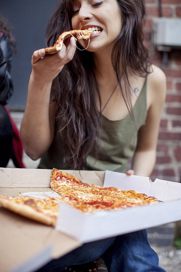 Mixed race woman eating pizza Photograph by Shestock