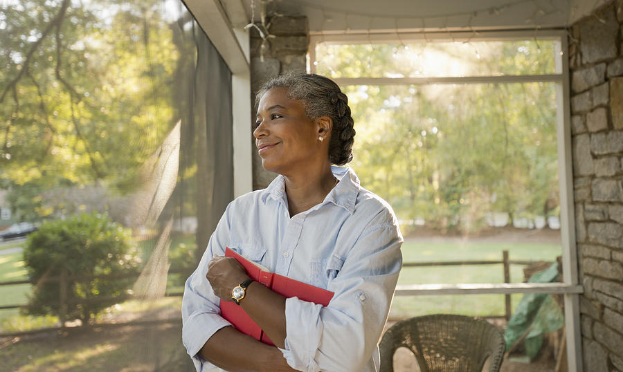 Mixed race woman holding book on porch Photograph by Mark Edward Atkinson/Tracey Lee