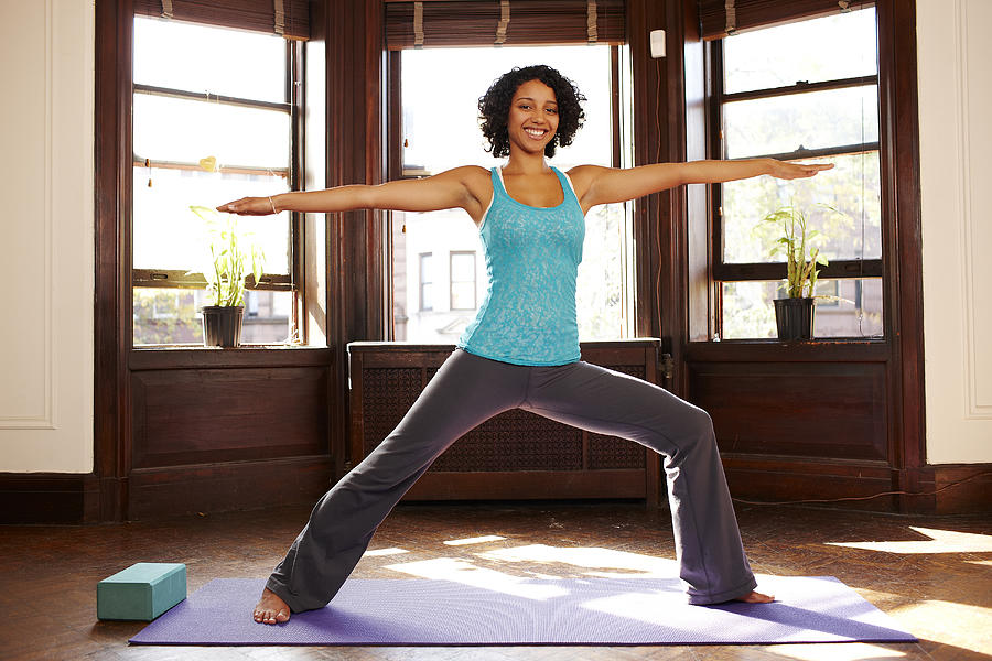 Mixed race woman practicing yoga in living room Photograph by Granger Wootz