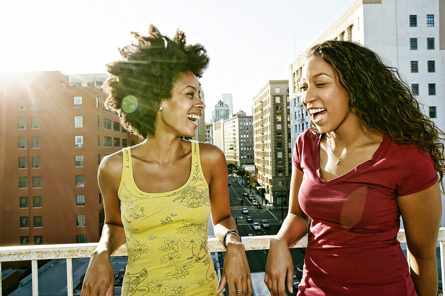 Mixed race women smiling on urban rooftop Photograph by Peter Griffith