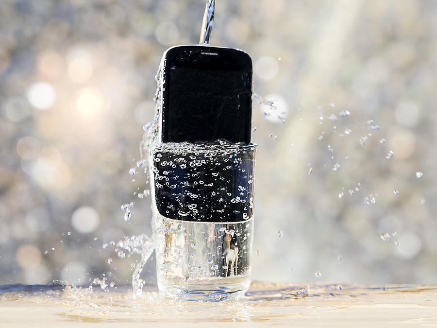 Mobile phone of last generation, resistant to the water inside a water glass Photograph by Jose A. Bernat Bacete