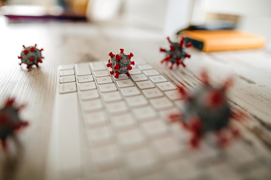 Model of corona virus on desk and keyboard in office Photograph by Mixetto