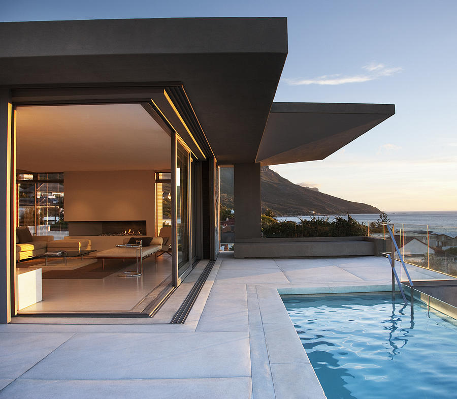 Modern living room and patio next to swimming pool Photograph by Martin Barraud