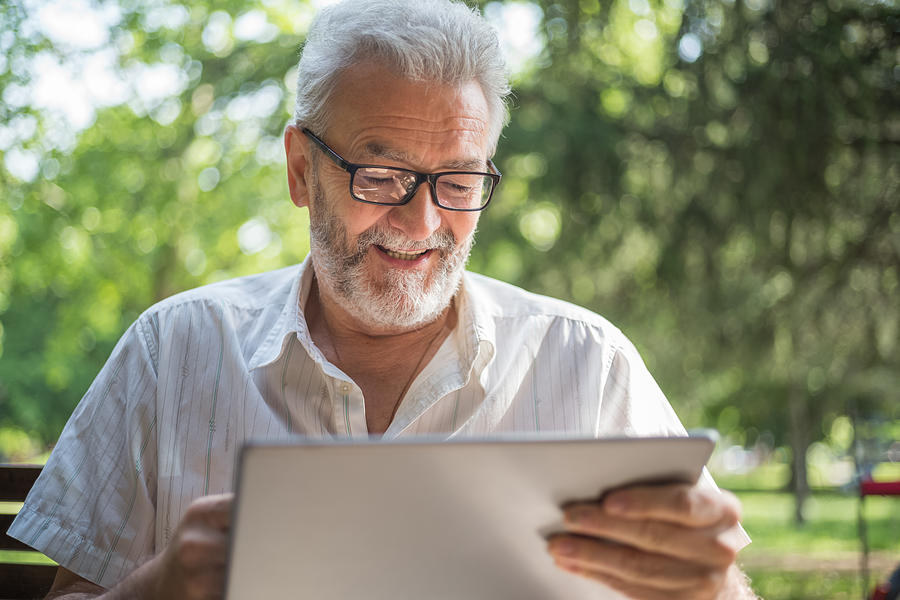 Modern senior man with tablet Photograph by Freemixer