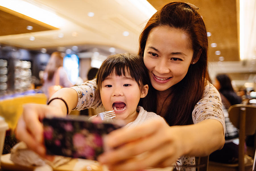 Mom & toddler girl taking selfie joyfully in cafe Photograph by images by Tang Ming Tung