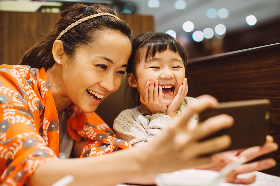 Mom & toddler taking selfies in restaurant Photograph by Images By Tang Ming Tung
