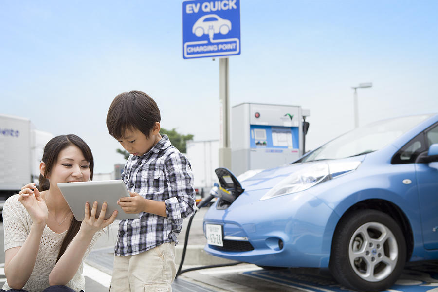 mom and child using tablet PC while charging car Photograph by Michael H