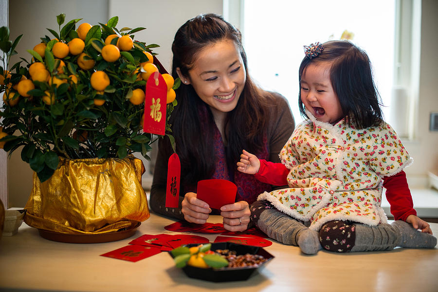 Mom decorating CNY tangerine tree with toddler Photograph by images by Tang Ming Tung