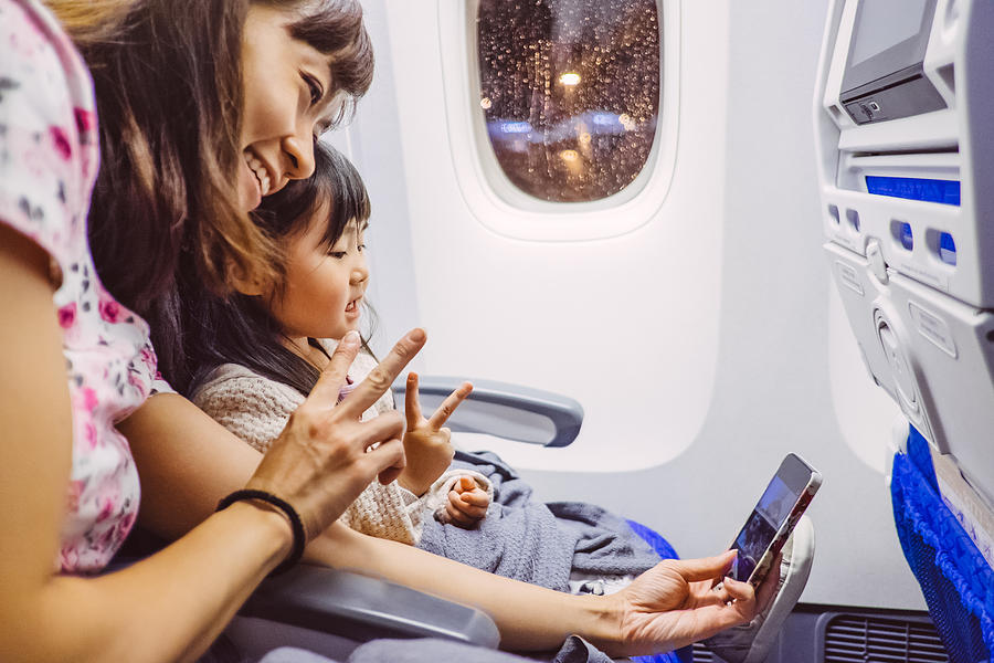 Mom taking selfies with child in airplane Photograph by Images By Tang Ming Tung