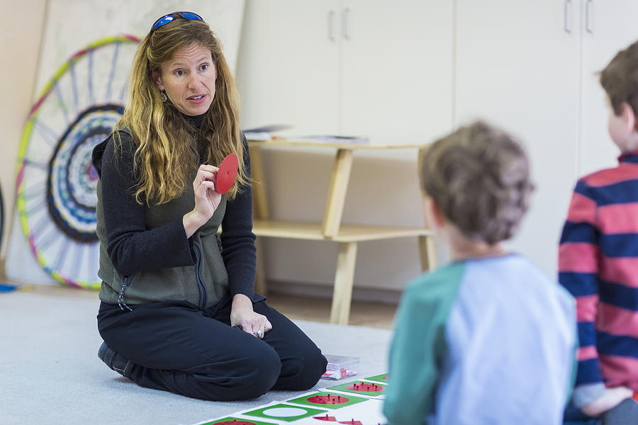 Montessori teacher talking to students in classroom Photograph by Marc Romanelli