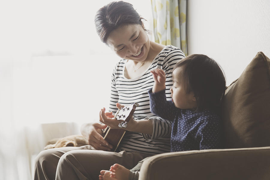 Mother and baby playing ukulele at home Photograph by Kohei_hara