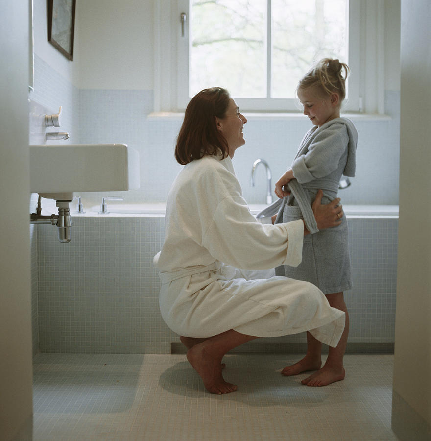 Mother and daughter (2-3) wearing dressing gowns in bathroom Photograph by Ryan McVay