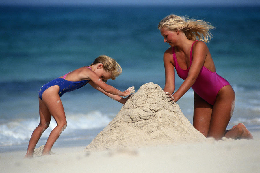 Mother and daughter (4-5) building sandcastle Photograph by David De Lossy