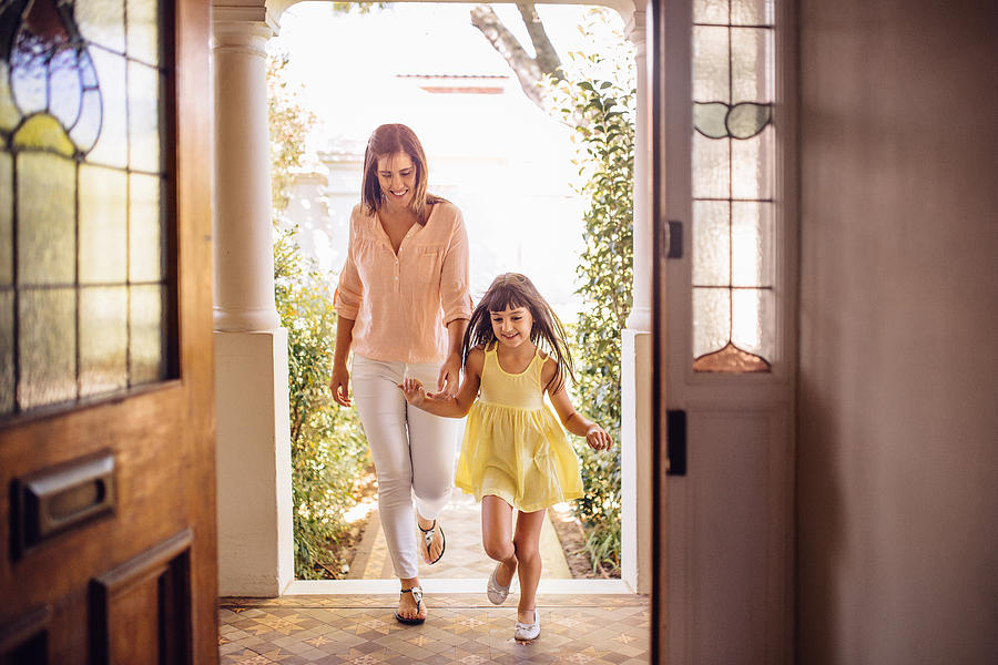 Mother and daughter arriving home through their front door Photograph by Wundervisuals