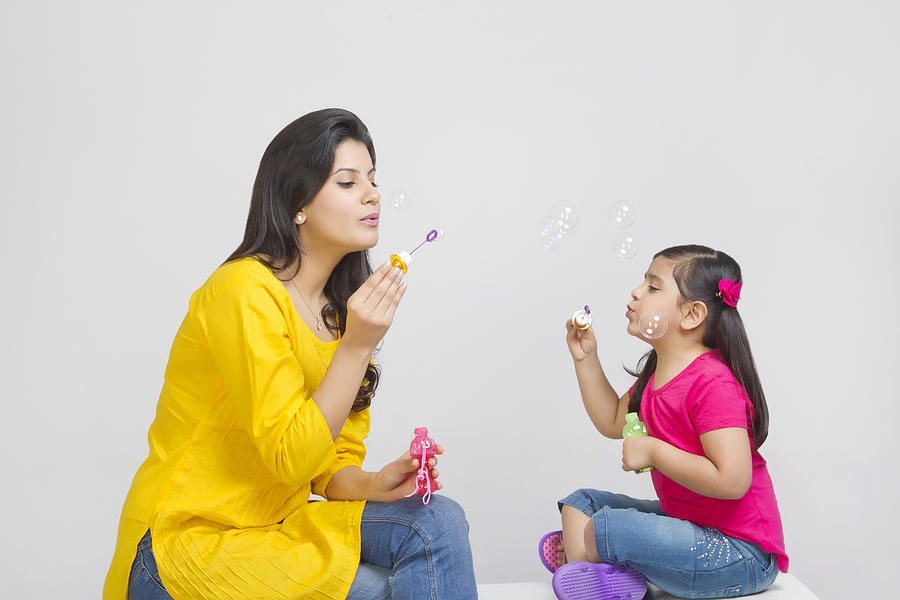 Mother and daughter blowing bubbles Photograph by IndiaPix/IndiaPicture