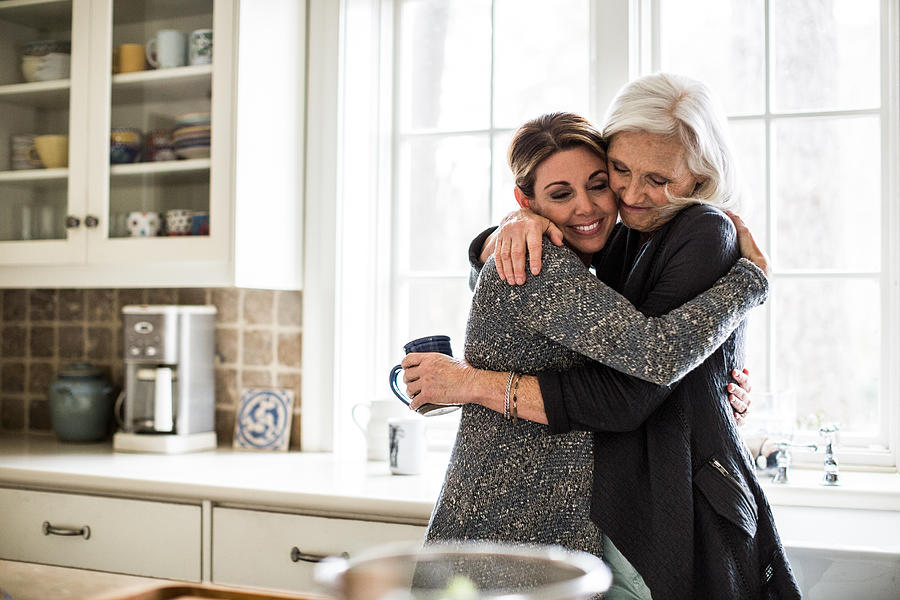 Mother And Daughter Hugging In Kitchen Photograph by MoMo Productions