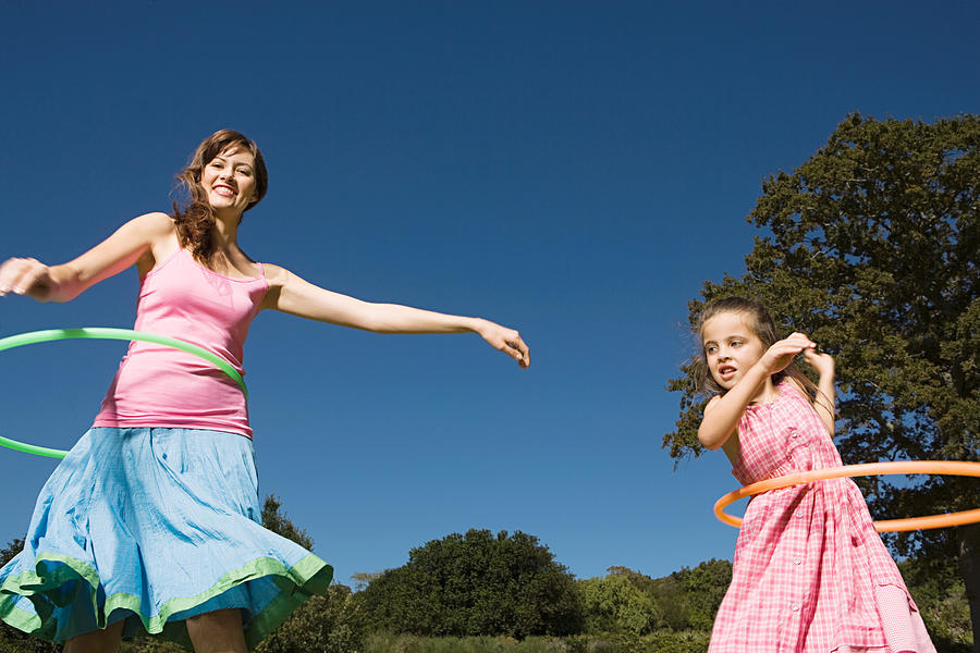 Mother and daughter hula hooping Photograph by Image Source