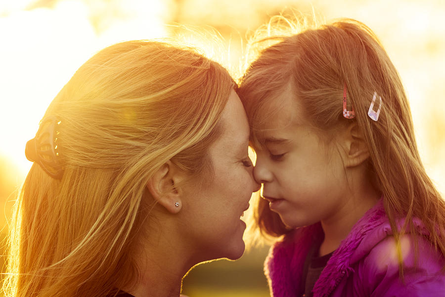Mother and daughter kissing at sunset closeup Photograph by IvanJekic