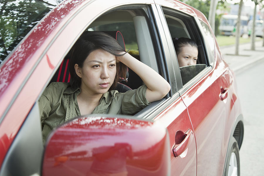 Mother and Daughter Looking Frustrated Out the Window of a Car Photograph by XiXinXing