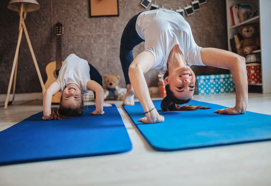 Mother and daughter working out together doing exercise at home Photograph by Zeljkosantrac