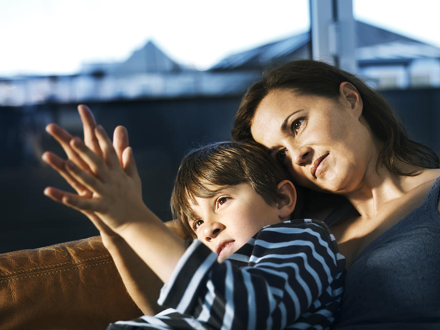 Mother and son (8-9) sitting on sofa, comparing palms Photograph by Henrik Sorensen