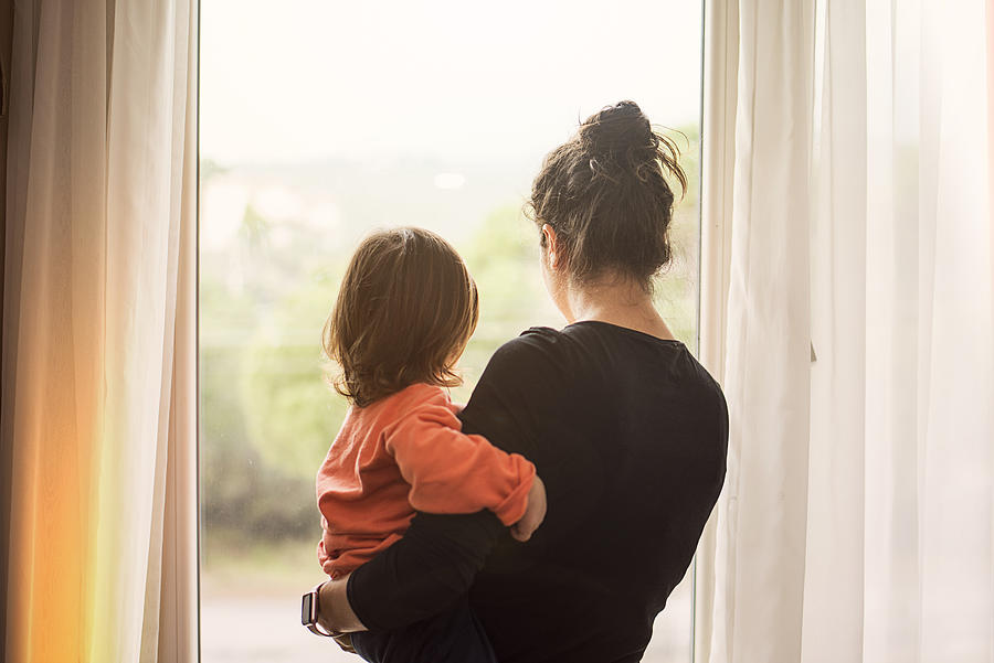 Mother and son looking out of window Photograph by Kaan Sezer