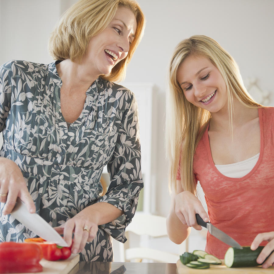 Mother and teenage daughter cooking together Photograph by Jamie Grill