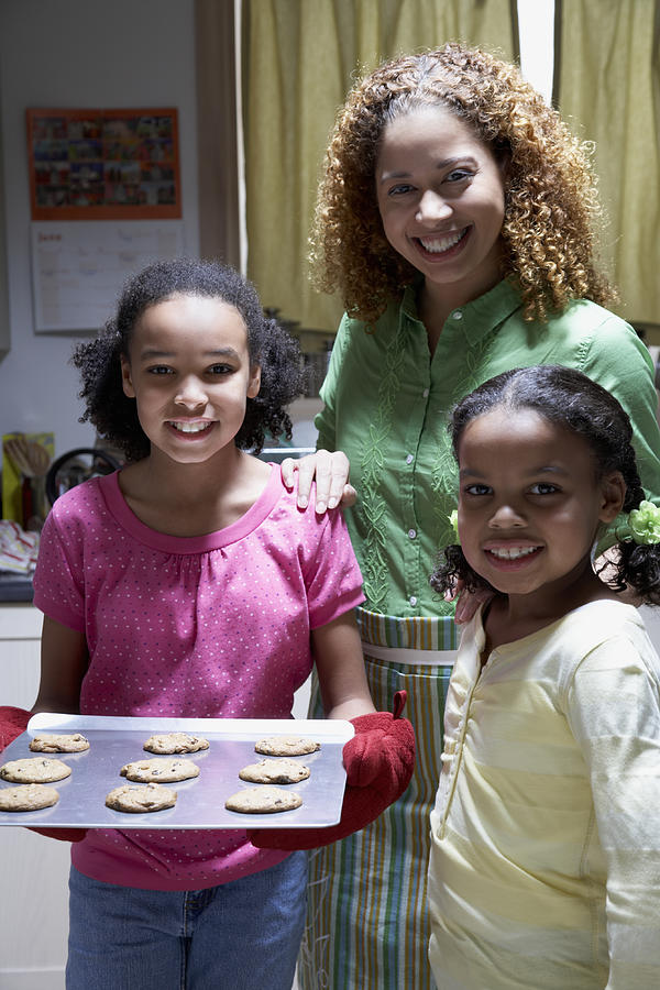 Mother and two daughters (8-12) with tray of cookies,smiling,portrait Photograph by Sean Justice