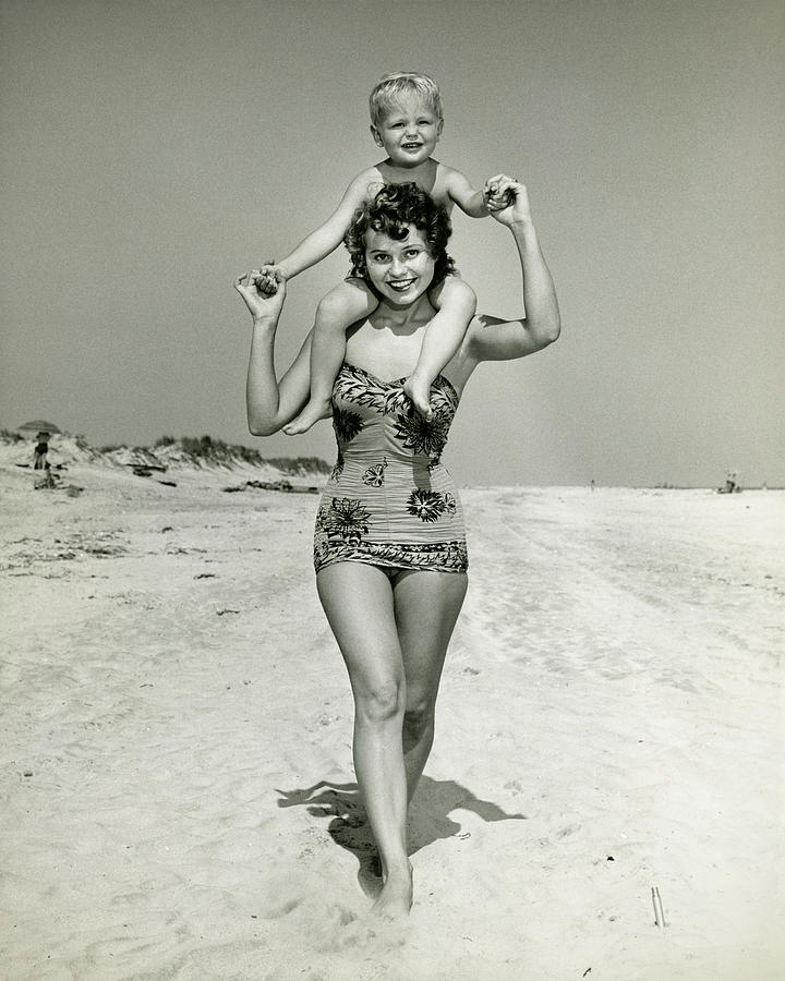 Mother carrying son (2-3) on shoulders, walking on beach, (B&W), portrait Photograph by George Marks