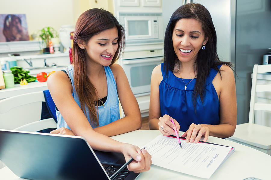 Mother helping daughter fill out College Applications in the Kitchen Photograph by SDI Productions