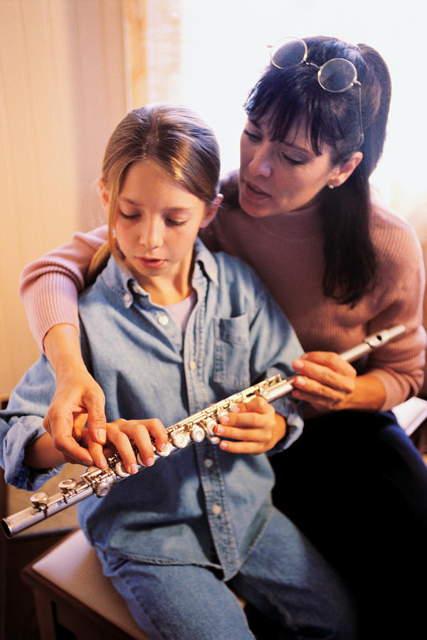 Mother helping daughter with flute Photograph by Thinkstock Images
