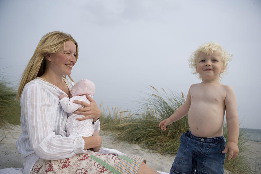 Mother holding baby girl (0-3 months) with baby boy (1-3) on beach Photograph by Jakob Helbig