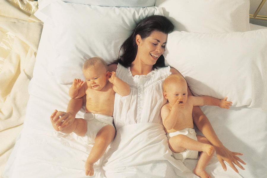 Mother in bed with twin children Photograph by Comstock