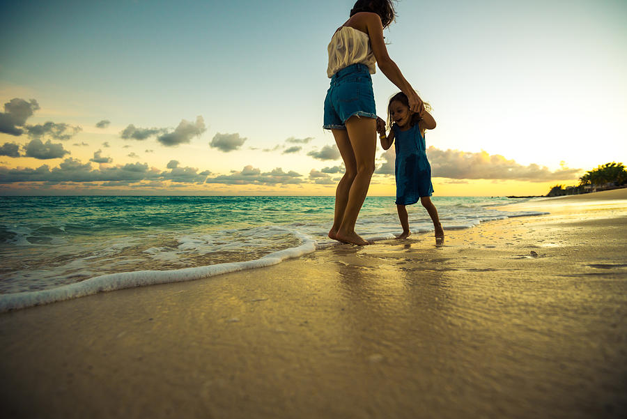 Mother playing with her daughter on the beach at sunset Photograph by Warchi