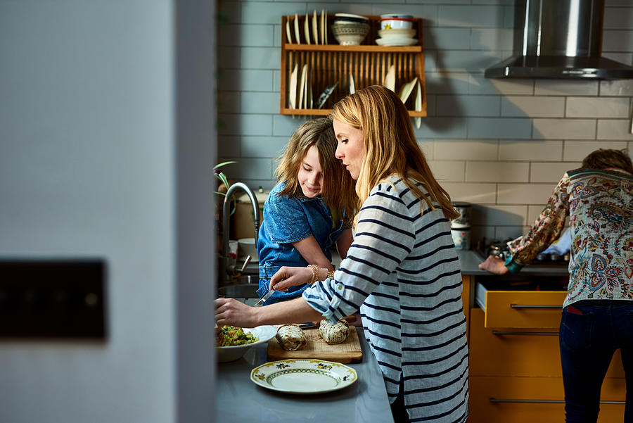 Mother serving lunch with daughter in kitchen Photograph by 10000 Hours