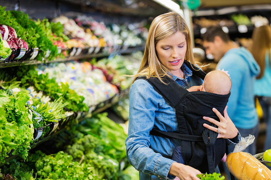 Mother shopping with infant daughter in grocery store or supermarket Photograph by SDI Productions
