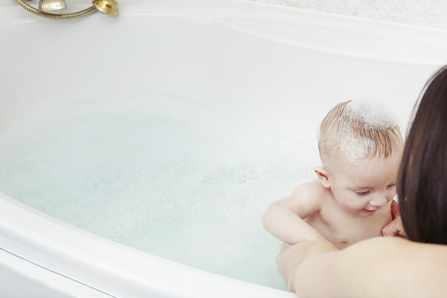 Mother washing baby girl in bubble bath Photograph by Emma Kim