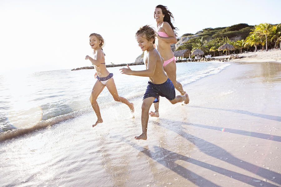 Mother with son (8-9) and daughter (10-11) running on beach Photograph by Felix Wirth