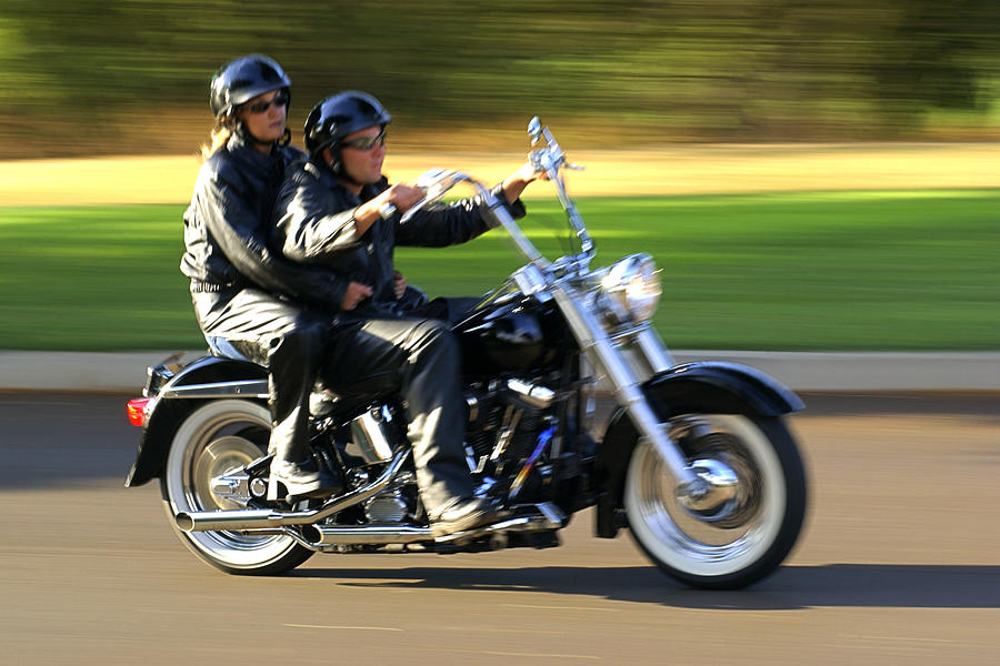 Motion blurred shot of a couple riding fast past the viewer on a motorcycle. Photograph by Thinkstock