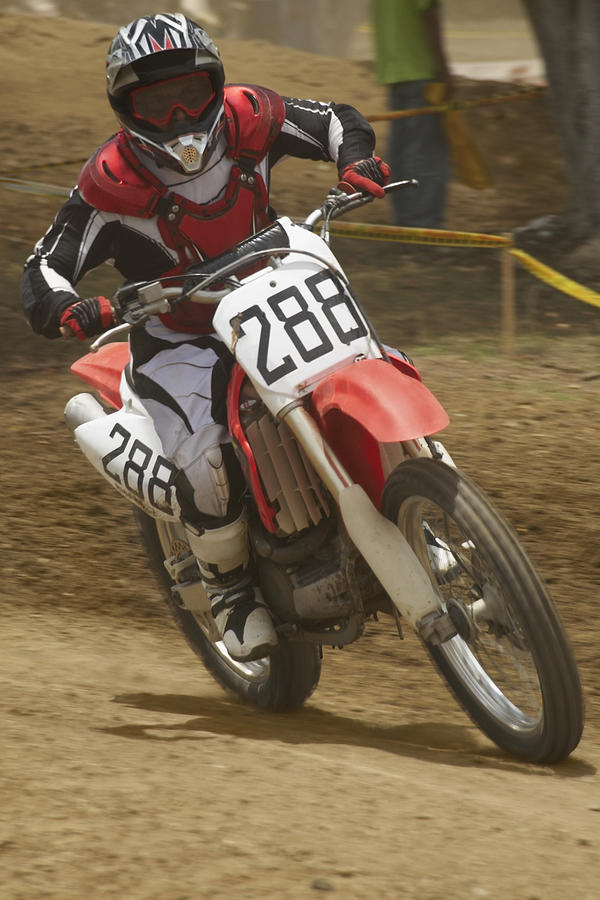 Motocross rider riding a motorcycle and leaning into a turn Photograph by Glowimages
