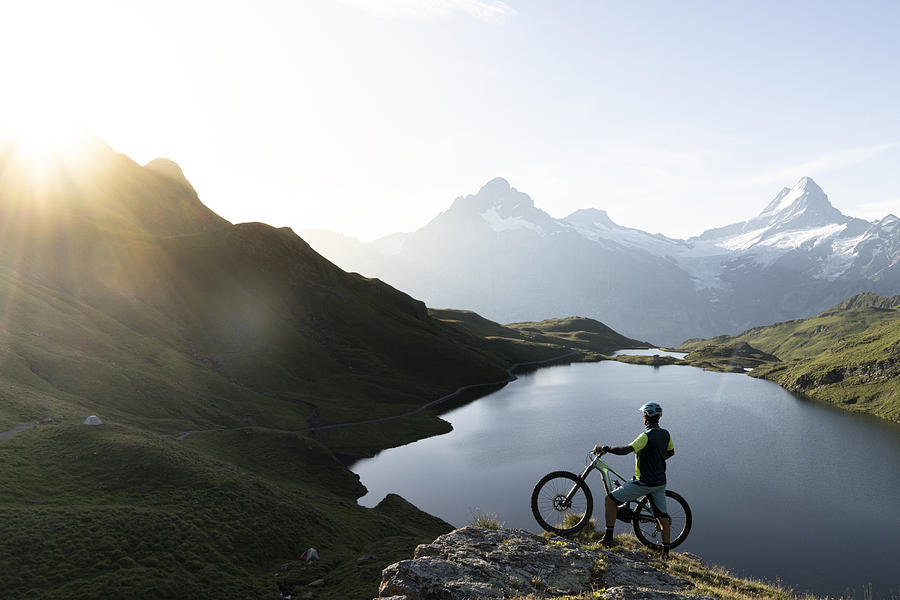 Mountain biker admiring sunrise at Bachalpsee lake, Switzerland Photograph by Roberto Moiola / Sysaworld