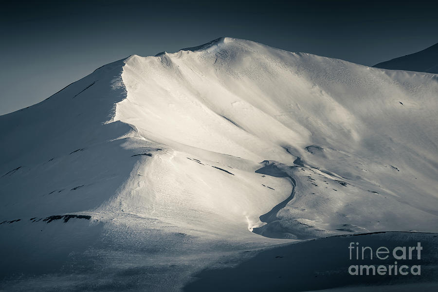 Mountain detail of a snowy peak in Svalbard, looking along the ridge. Split toned, low key image. Photograph by Jane Rix