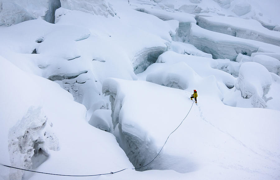Mountaineer in snow trying to find a way around crevasses Photograph by DennisHabarov