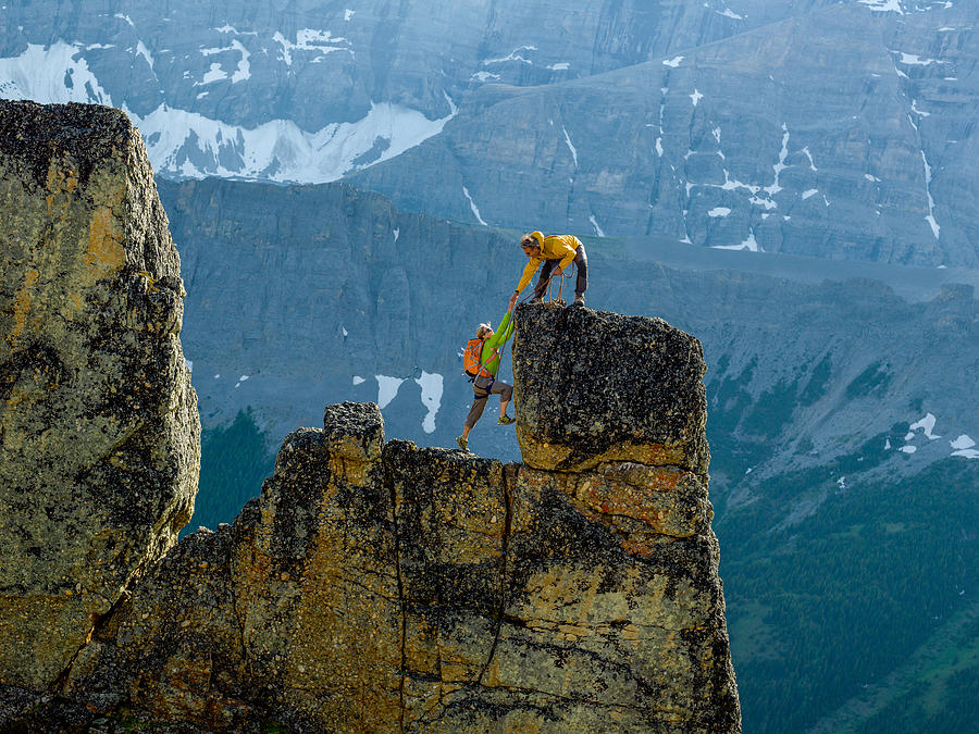 Mountaineers scale rocks steps on cliff with rope Photograph by AscentXmedia