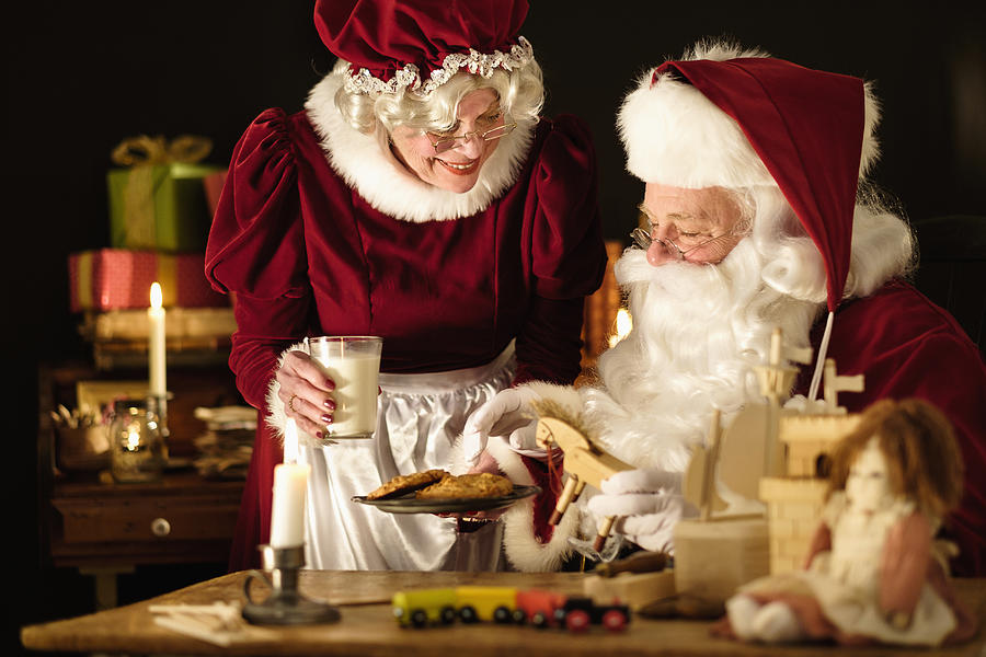 Mrs. Claus bringing homemade cookies to Santa Claus Photograph by Tetra Images