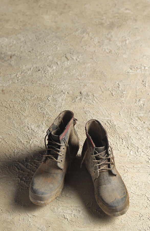 Muddy boots on concrete background Photograph by Peter Dazeley